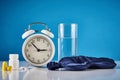 Insomnia problem and sleeping trouble concept. Alarm clock, glass of water, ear plugs and pills on the blue background Royalty Free Stock Photo