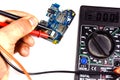 Inspecting of the electronic circuit board with multimeter. Whit Royalty Free Stock Photo