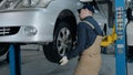 Inspection of the chassis of the car. A young mechanic in uniform works in a car service with a lifted car. Car repair Royalty Free Stock Photo