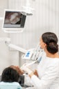 Inspection with a dental macro camera and displays the result on the monitor. Young woman dentist treating root canals