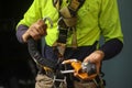 Inspector clipping locking Karabiner into front of full body safety abseiling harness loop