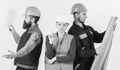 Inspector disappointed about employee, builder. Men and woman in helmets carefree with hammer and project
