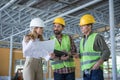 Inspector holding blueprint and looking at workers in hard hats Royalty Free Stock Photo