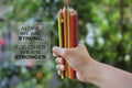 Inspiratinal quote - Alone we are strong. Together we are stronger. With young woman hand holds bunch of pencil colored and blurry