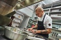 Inspiration in cooking. Young male chef with several tattoos on his arms is garnishing italian pasta in a restaurant Royalty Free Stock Photo