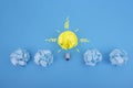 Idea of solution. Concept Lamp with crumpled paper on a blue background, be different