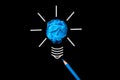 Light bulb with crumpled colorful paper and blue pencil on black background.