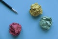 Inspiration or idea concept. A pen with a colorful crumpled paper balls on a blue background Royalty Free Stock Photo