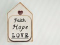 Inspirational concept - faith, hope, love text written on wooden frame background. Stock photo.