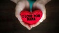 inspirational love concept - i love you mama text on red heart shaped pillow on kid& x27;s hands