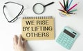 motivation life quote on notepad - We Rise by Lifting Others