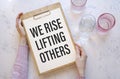 Inspirational and motivation life quote on notepad text we rise lifting others