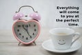 Inspirational motivational quote - Everything will come to you at the perfect time. With alarm clock and a smile on cup of coffee.