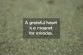 Inspirational motivational quote - A grateful heart is a magnet for miracles. With blurry black sands pattern texture background.