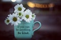 Inspirational motivational quote - If you can be anything. Be kind. With cup of coffee or tea with white daisy flowers. Royalty Free Stock Photo