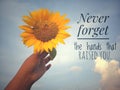 Inspirational motivational quote - Never forget the hands that raised you. With background of blue sky and beautiful sunflower