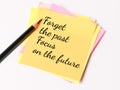 Phrase forget the past focus on the future written on sticky note with a pencil.