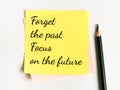 Phrase forget the past focus on the future written on sticky note with a pencil.