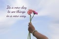 Inspirational motivational quote - It`s a new day to see things in a new way. With hand holding a bouquet of pink daisy flowers.