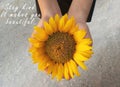 Inspirational motivational quote - Stay kind. It makes you beautiful. With background of sunflower blossom in open hands.