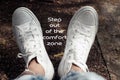 Inspirational motivational quote- Step out of the comfort zone. With relax feet of young woman in white sneakers background