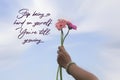 Inspirational motivational quote - Stop being so hard on yourself, you`re still growing. A hand showing soft pink flowers on sky