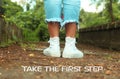 Inspirational motivational quote- Take the first step. With feet of young woman in white sneakers standing from back. Green nature