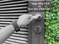 Inspirational motivational quote - Take the risk or lose the chance. With hand of a person holding doorknob opening wooden door. Royalty Free Stock Photo