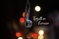 Inspirational motivational quote - Together forever. With two white earphone hanging together on colorful bokeh light background. Royalty Free Stock Photo