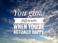 Inspirational motivational quote - You glow differently when you are actually happy. On background of  bright blue sky and clouds Royalty Free Stock Photo