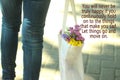 Let things go and move on. Concept photo with young woman legs wearing jeans carrying a white bag full of colored flowers