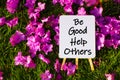 Be good help others. On background of pink flowers and green grass.