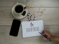 Inspirational quote - Be inspired. With morning coffee, phone and hand writing on note book white paper. Royalty Free Stock Photo