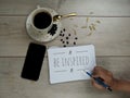 Inspirational quote - Be inspired. With a cup of white coffee, phone and note on spiral white notebook on wooden table background