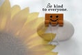 Inspirational quote - Be kind to everyone. With smile symbol on yellow paper clip and blurry sunflower on white background. Royalty Free Stock Photo