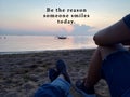 Inspirational quote - Be the reason someone smiles today. With blurry image of two best friends together sitting on sands enjoying