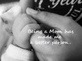 Inspirational quote- Being a Mom has made me a better person. With blurry image of a fragile little baby new born hand and fingers