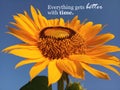 Inspirational quote- Everything gets better with time. With beautiful smiling sunflower blossom closeup. Blue sky background