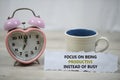 Inspirational quote - Focus on being productive instead of busy. With alarm table clock and a cup of morning coffee. Royalty Free Stock Photo