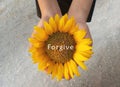 Inspirational quote - Forgive. With background of sunflower blossom in an open hands. Forgiving words of wisdom concept. Royalty Free Stock Photo