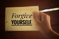 Inspirational quote - Forgive yourself. With a paper note in young woman hand on light brown background. Reminder and note to self Royalty Free Stock Photo