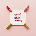 Inspirational quote good vibes only handwritten with watercolor in calligraphy style, miniature clothespins on a pale pink pastel