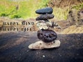 Inspirational quote - Happy mind, happy life. With sea stones balance formation on rock background. Life in balance concept.