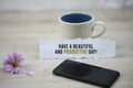 Inspirational quote - Have a beautiful and productive day. With morning a cup of coffee, black smartphone and purple daisy flower