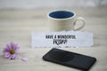 Inspirational quote - Have a wonderful Friday. With a cup of Friday morning coffee, purple daisy flower and a black cellphone. Royalty Free Stock Photo