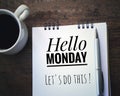 Inspirational quote - Hello Monday. Lets do this. Handwriting text written on a white notebook with pen and a white cup of morning