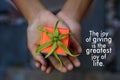 Inspirational quote - The joy of giving is the greatest joy of life. With a small cute gift box in young woman hands.