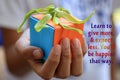 Inspirational quote - Learn to give more, and expect less. You will be happier that way. With young woman hand holding a gift. Royalty Free Stock Photo