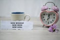 Inspirational quote - New Monday, New Week, New Goal. With note a cup of coffee, pink desk clock and purple daisy flower. Royalty Free Stock Photo