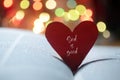 Inspirational quote on a red heart - God is good. Love sign on open bible book page and colorful bokeh lights background. Royalty Free Stock Photo